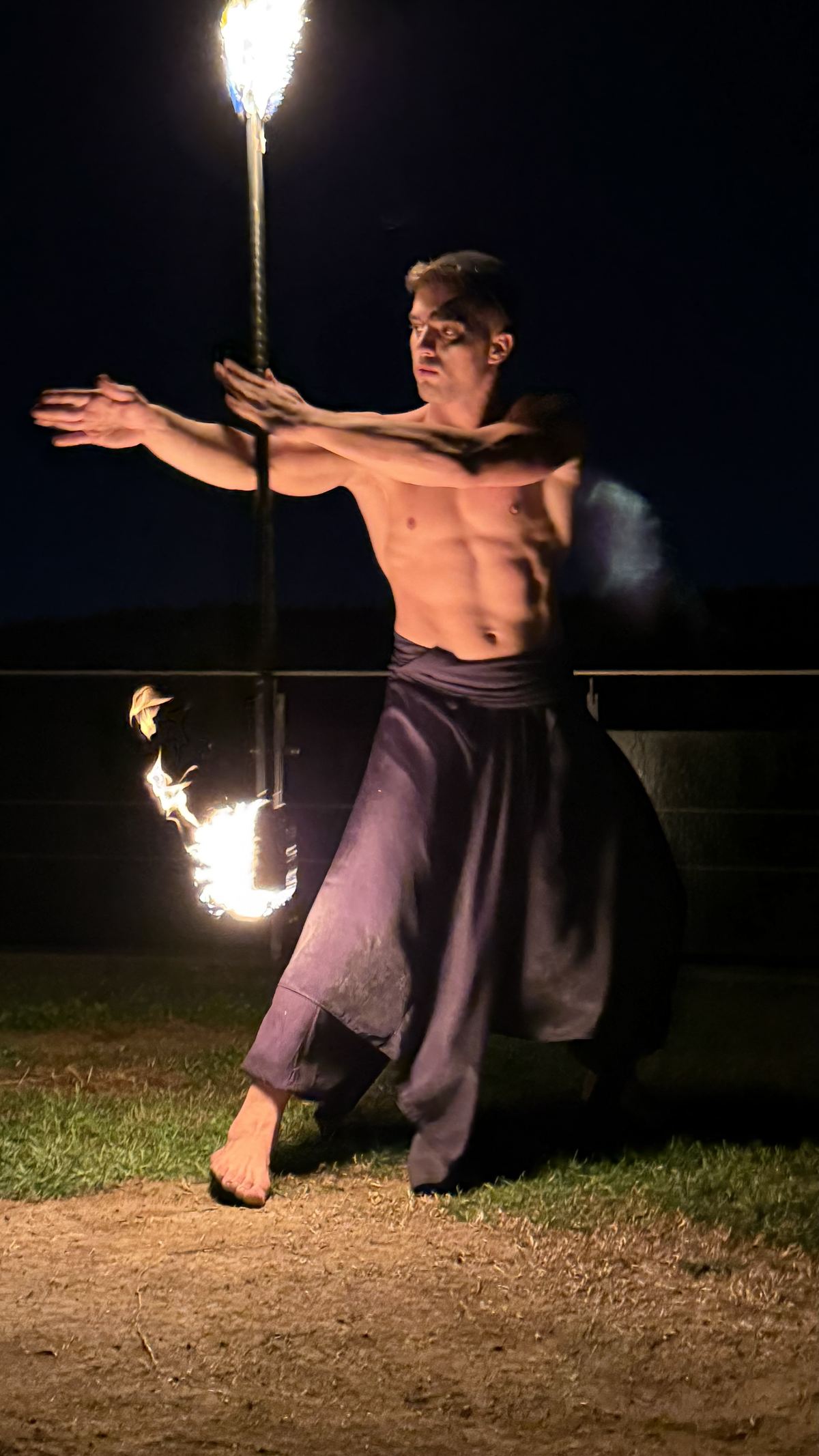 Çimende fire staff ile dönen performansçı, alevler havada