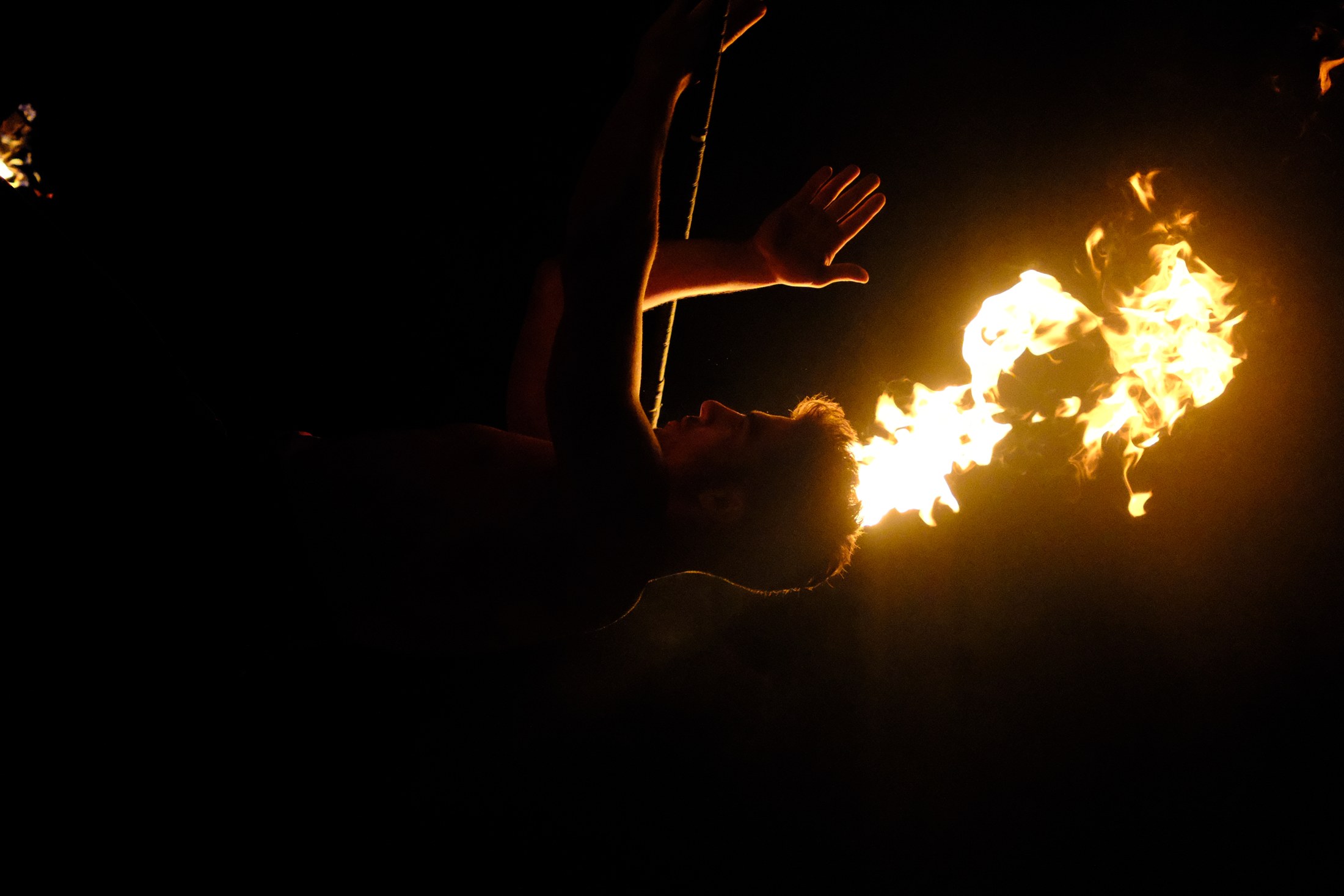 Karanlıkta geniş alev yayı çizen fire staff performansı
