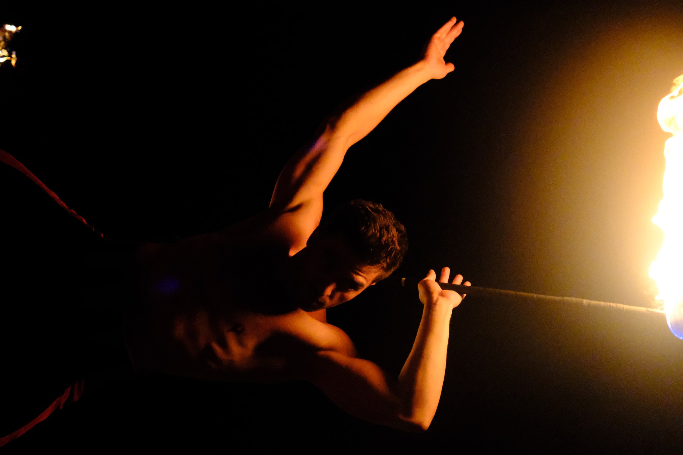 Alevli çubuğu iki eliyle savuran performansçı, arkada gece